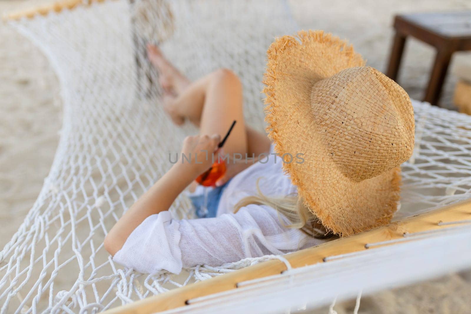 woman with cocktail relaxed in hammock.
