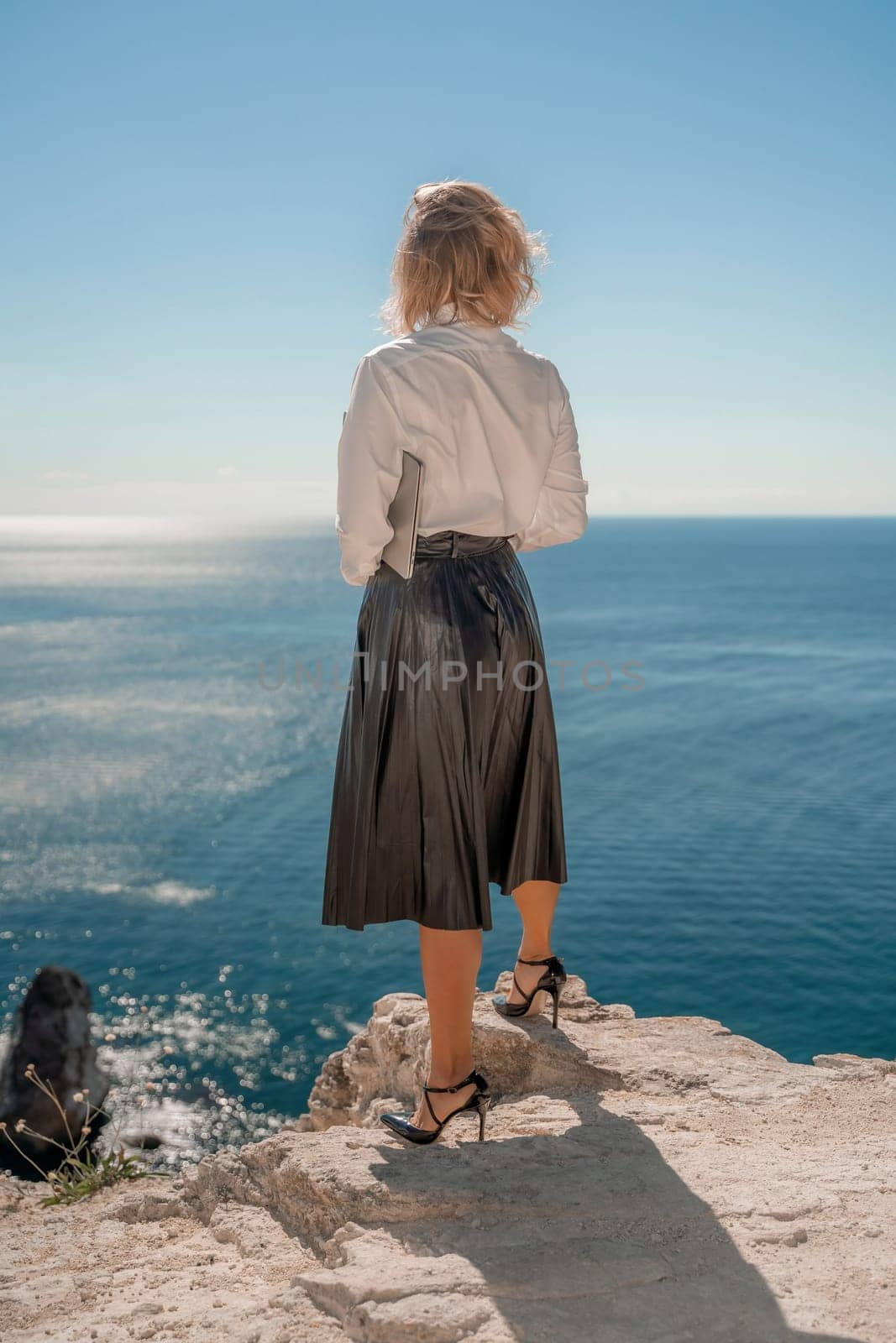 Freelance women sea working on a computer. Pretty middle aged woman with computer and phone outdoors with beautiful sea view. The concept of remote work