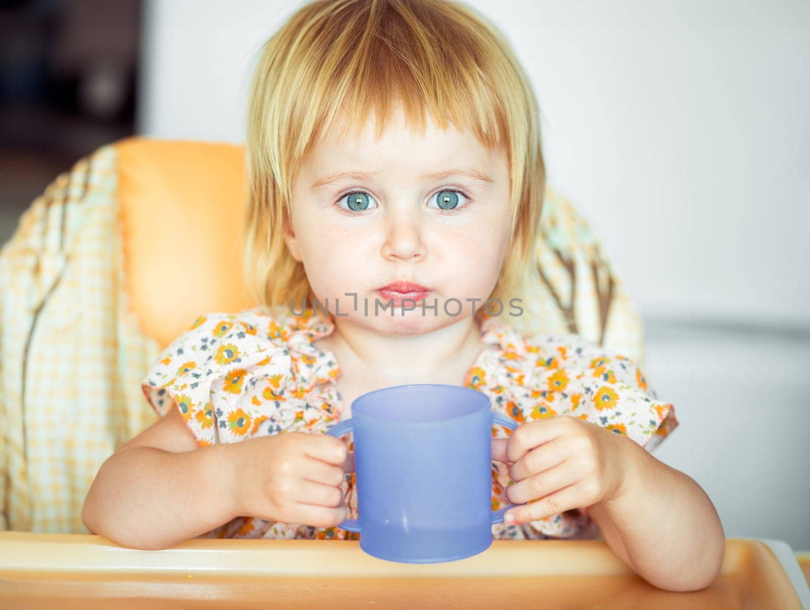 beautiful little girl sitting in a highchair and drinks