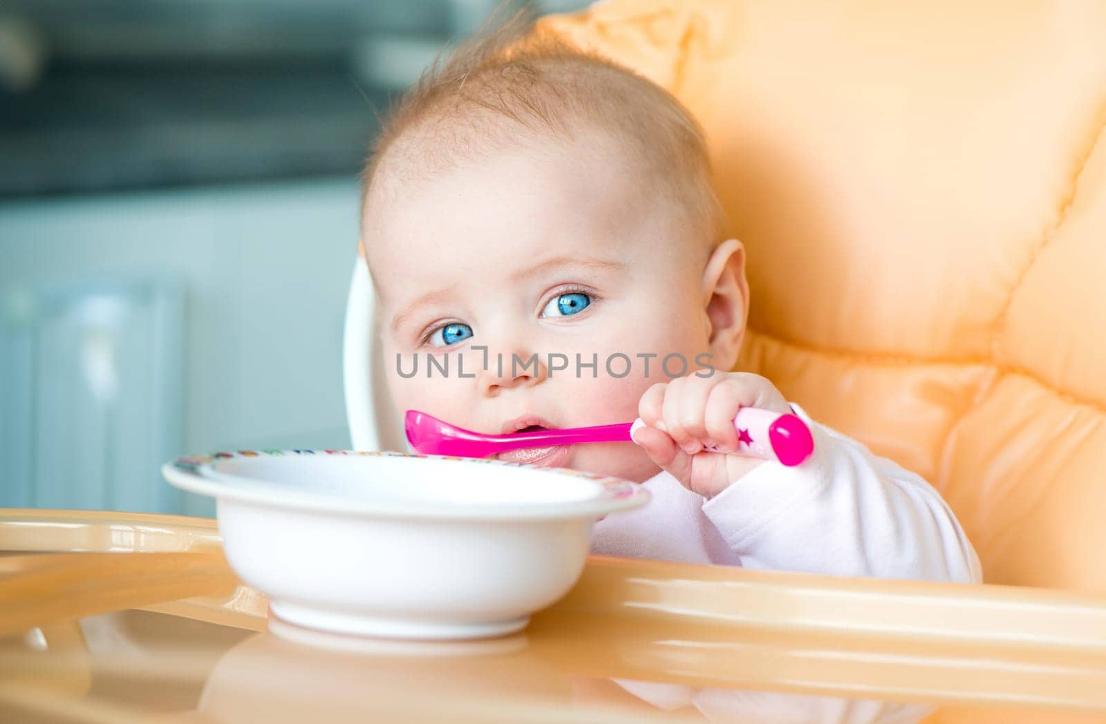 smiley baby girl is holding a spoon in her mouth and going to eat