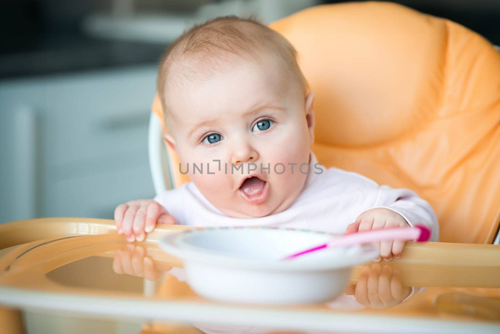 smiley baby girl is holding a spoon in his mouth and going to eat
