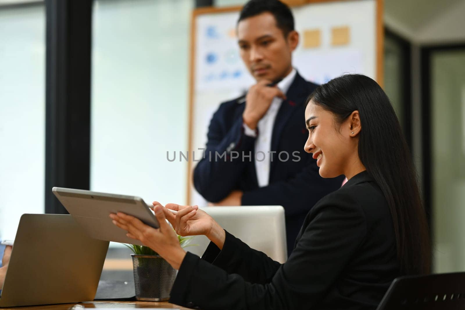 Confident businesswoman explaining project details, talking about company strategy and business plan during meeting.