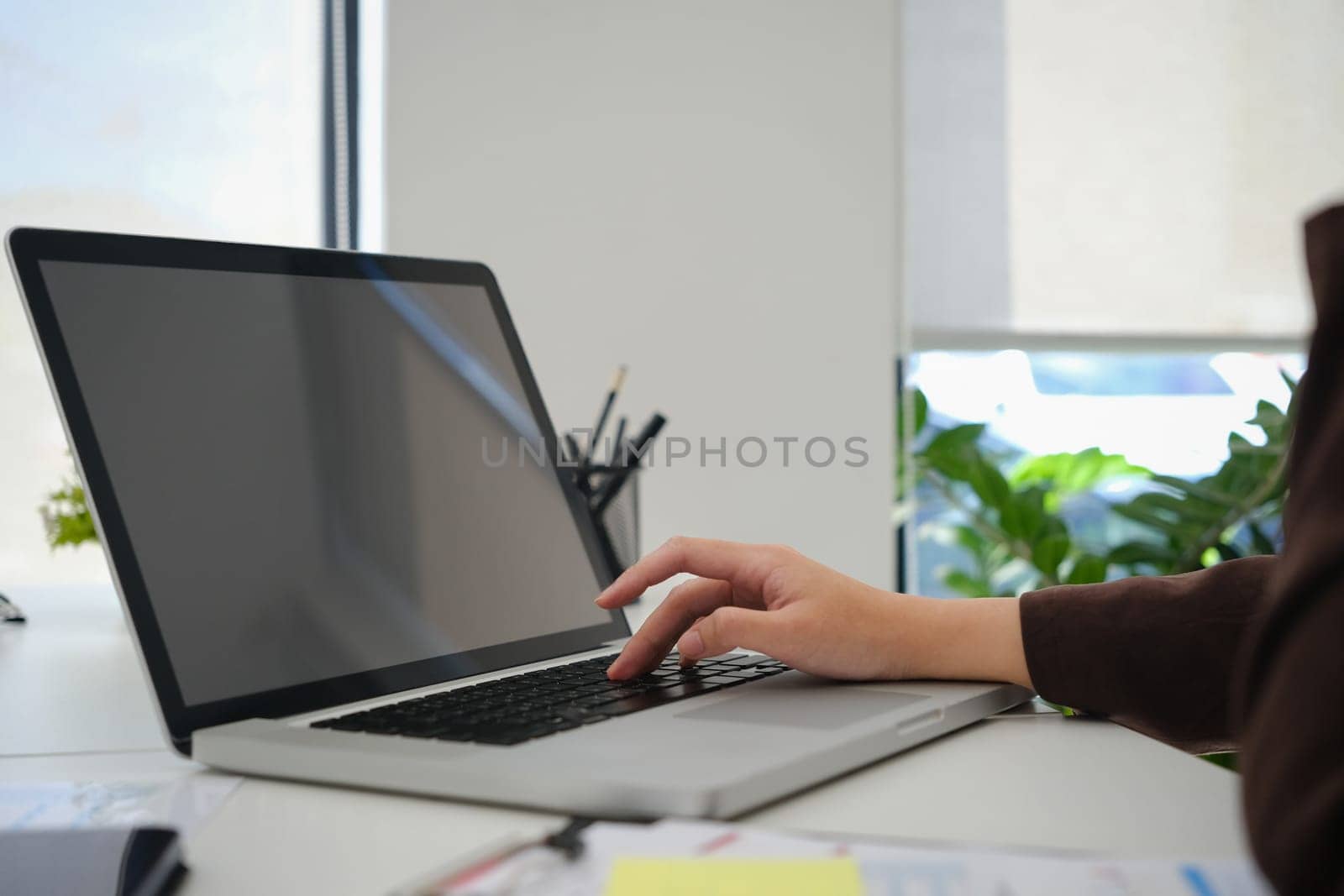 Closeup view female entrepreneur searching online information on laptop, working with reports at office.