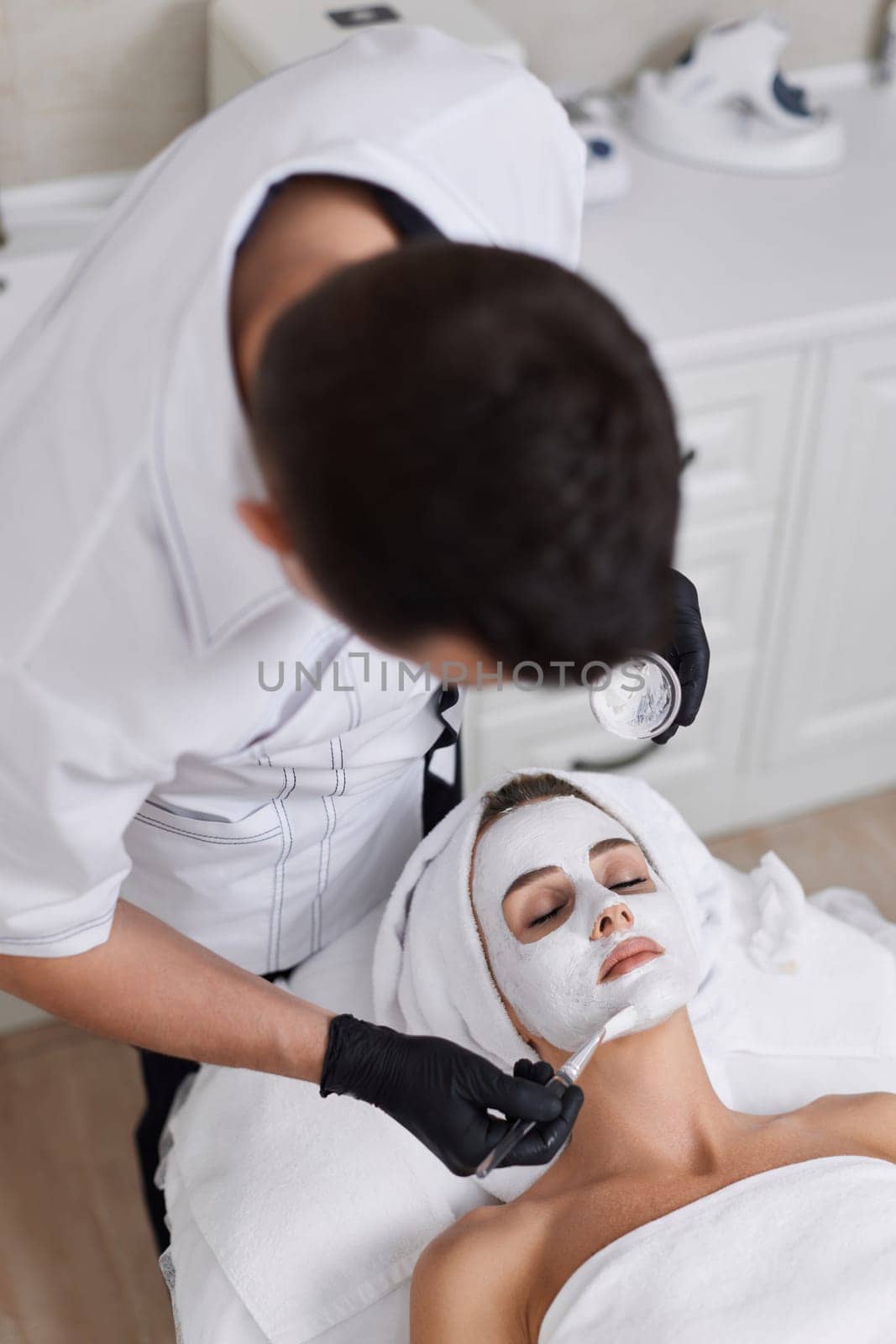 beautician applies the mask to face of woman in the spa salon. skin care by erstudio