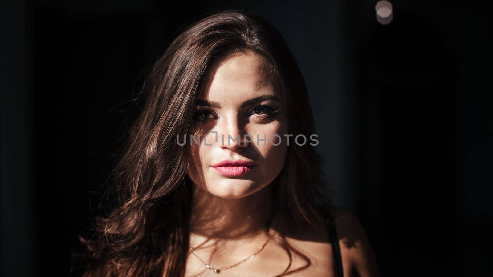 Portrait of a sexy brunette in a black dress on a dark background. girl takes off her dress slowly in the bedroom by malyshph