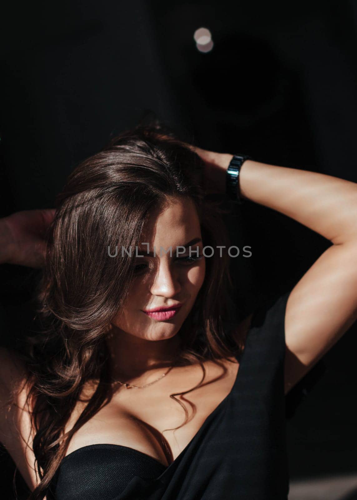 Portrait of a sexy brunette in a black dress on a dark background. girl takes off her dress slowly in the bedroom by malyshph