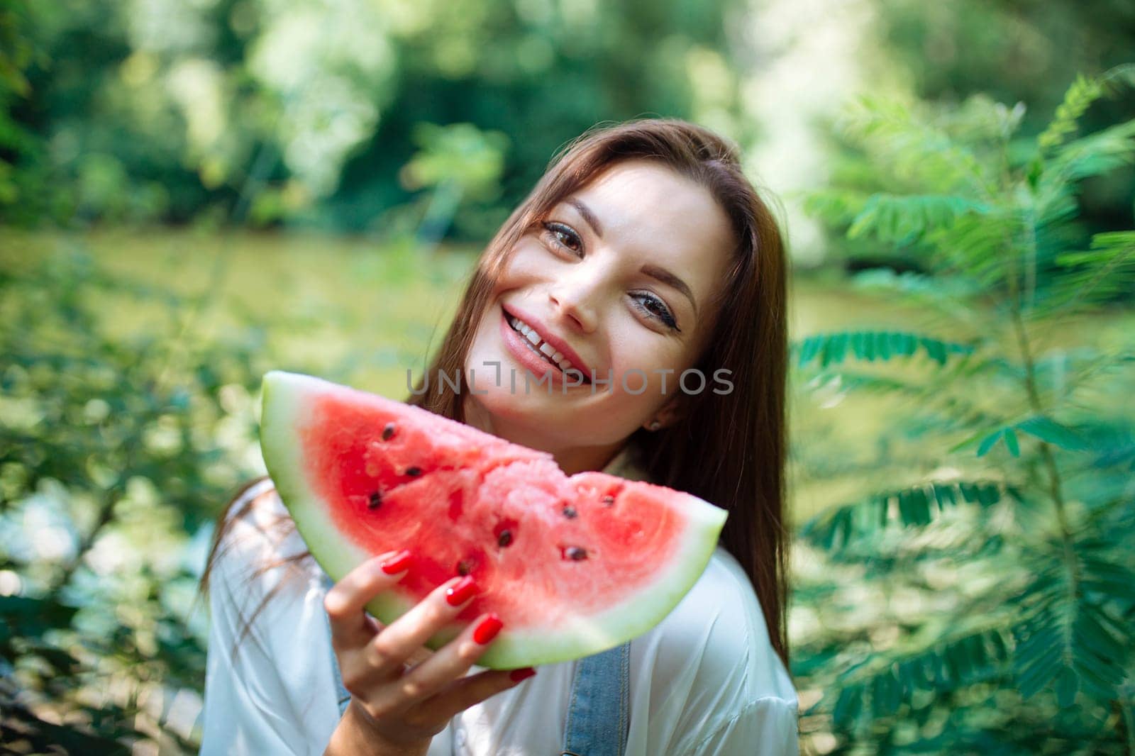 Picnic in nature and healthy eating. A sexy girl in the woods eats watermelon. Portrait of a woman with a berry in her hands.close-up