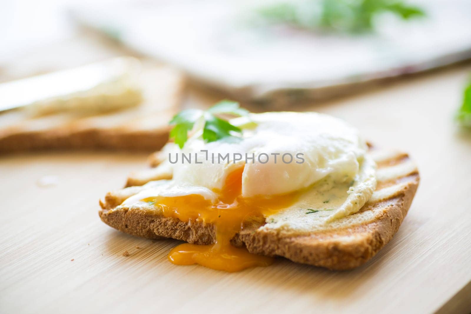 Fried toast bread with spread and poached egg, on a wooden table. Quick breakfast.