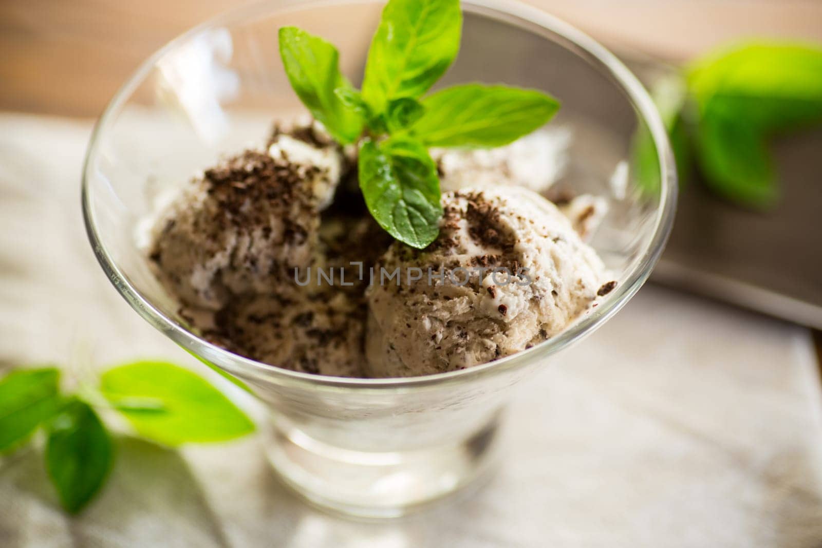 homemade ice cream with pieces of grated dark chocolate, in a bowl on a wooden table.