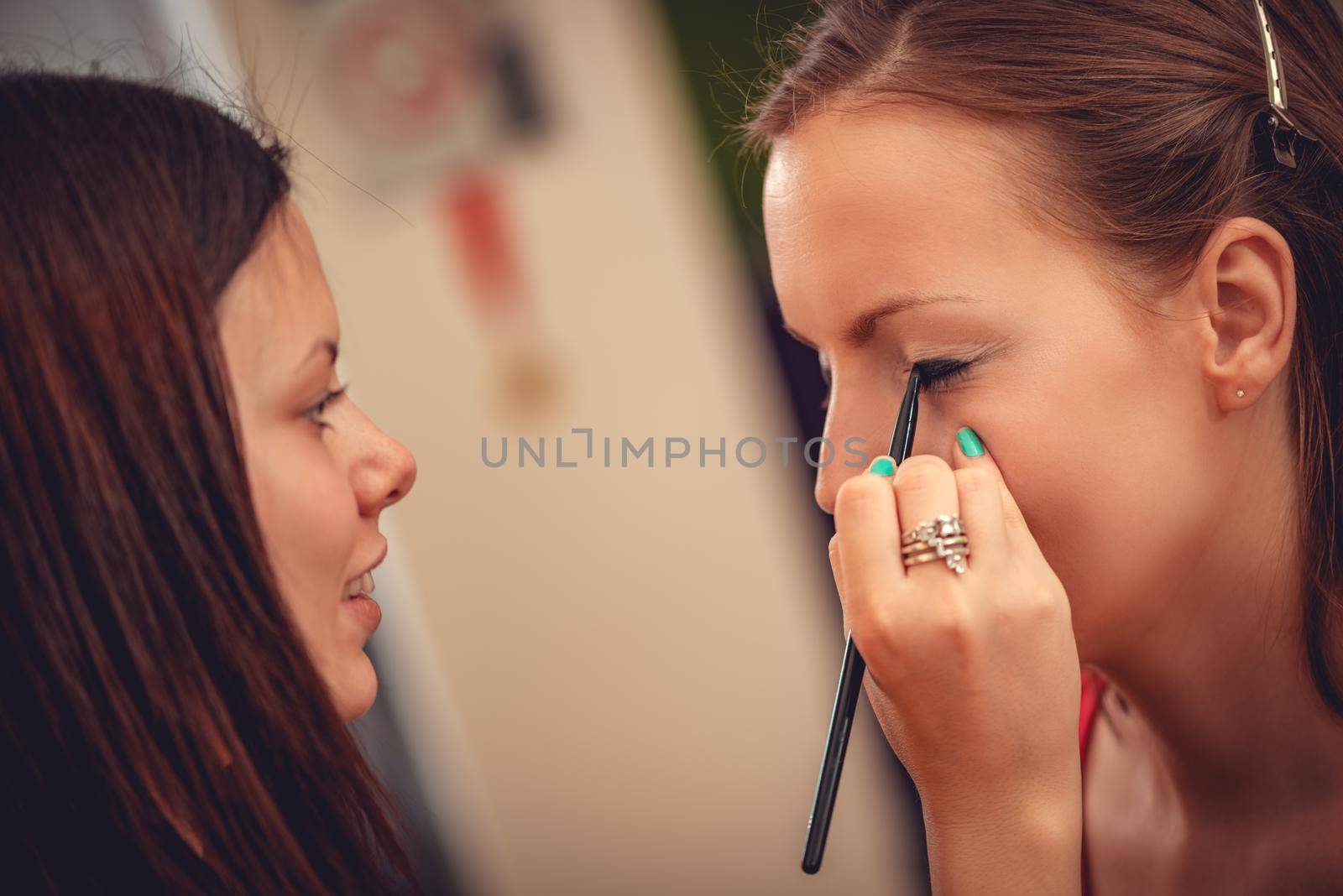 Close-up of a makeup artist getting eyeliner to model.