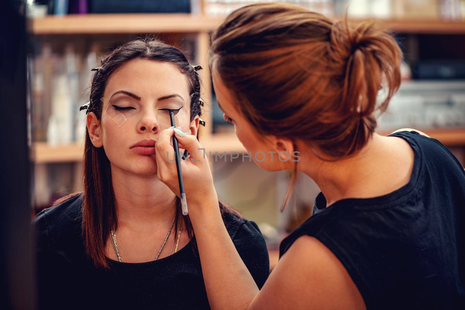 Make-up artist applying the eyeliner to model. 
