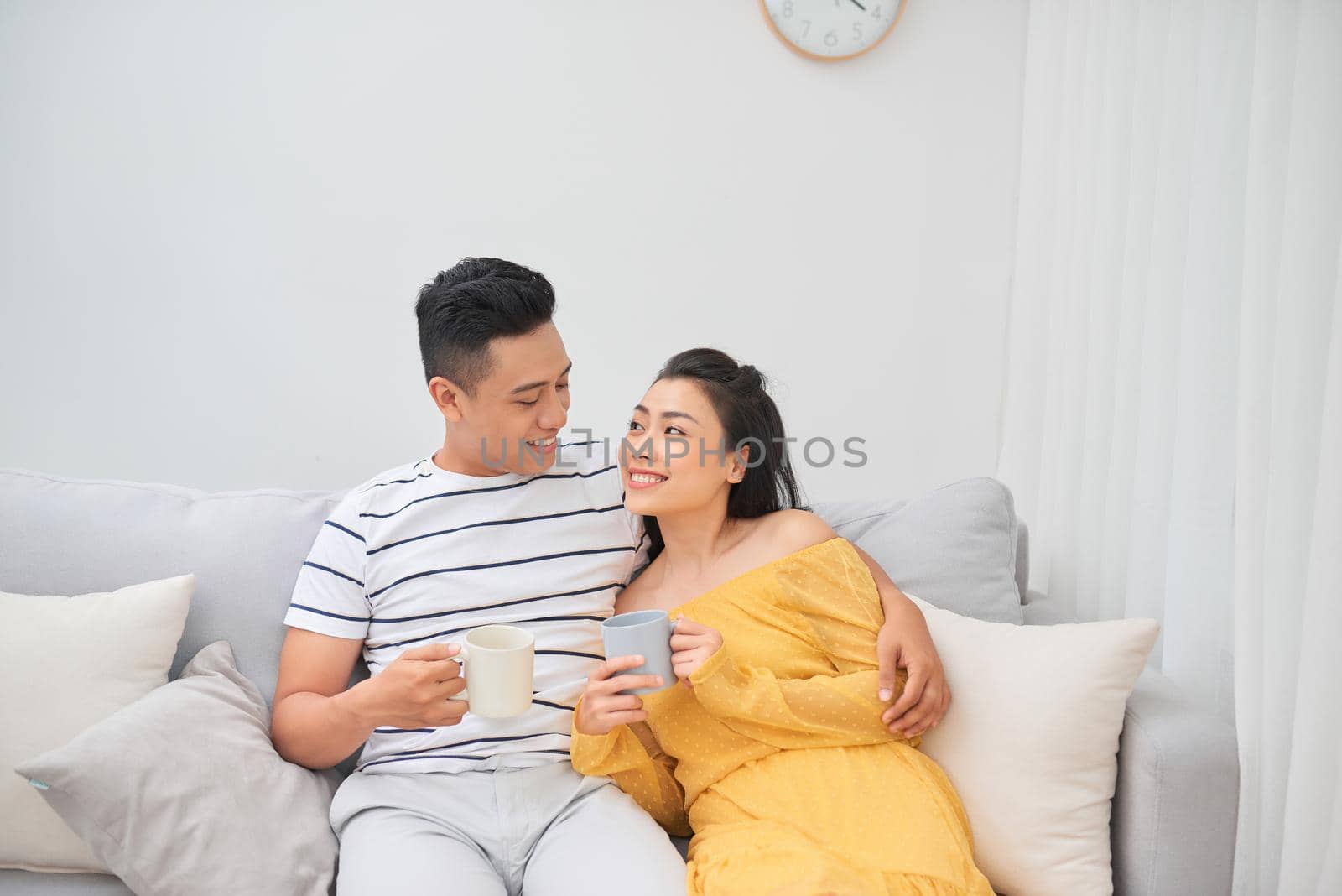 Couple in love enjoying their free time, sitting on a couch,drinking coffee and chatting.