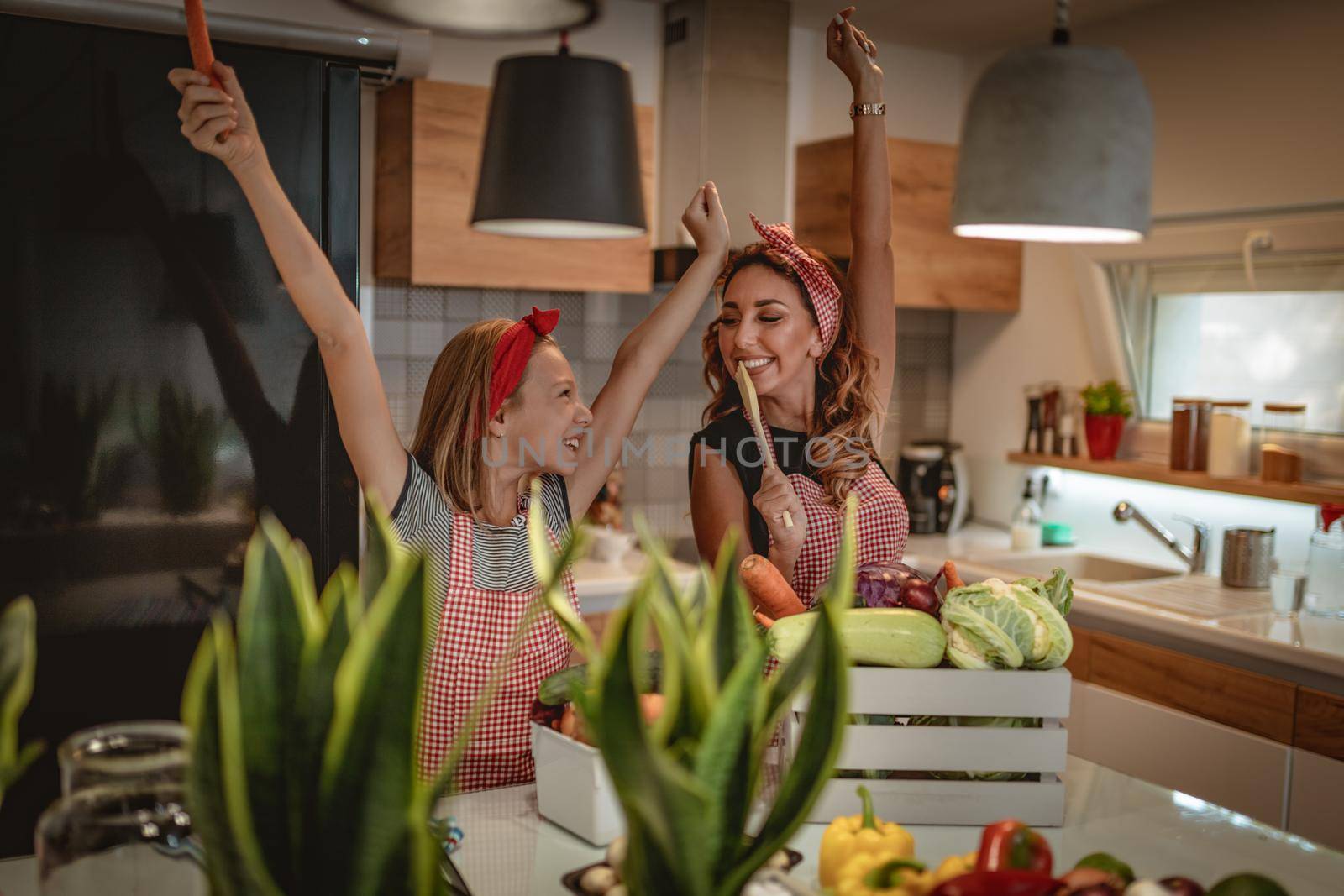 Happy mother and her daughter enjoy and having fun in making and having healthy meal together at their home kitchen.