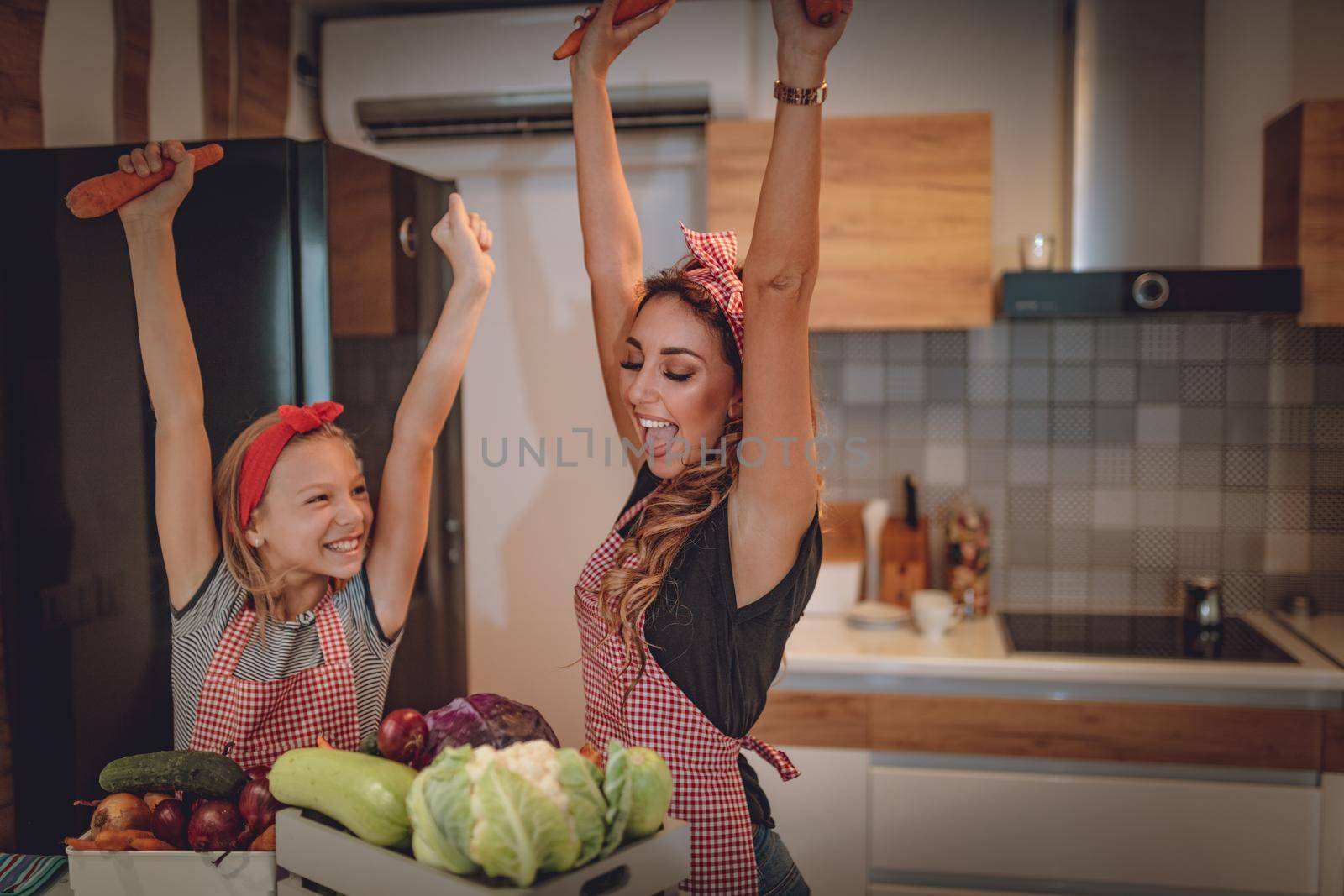 Happy mother and her daughter enjoy and having fun in making and having healthy meal together at their home kitchen.