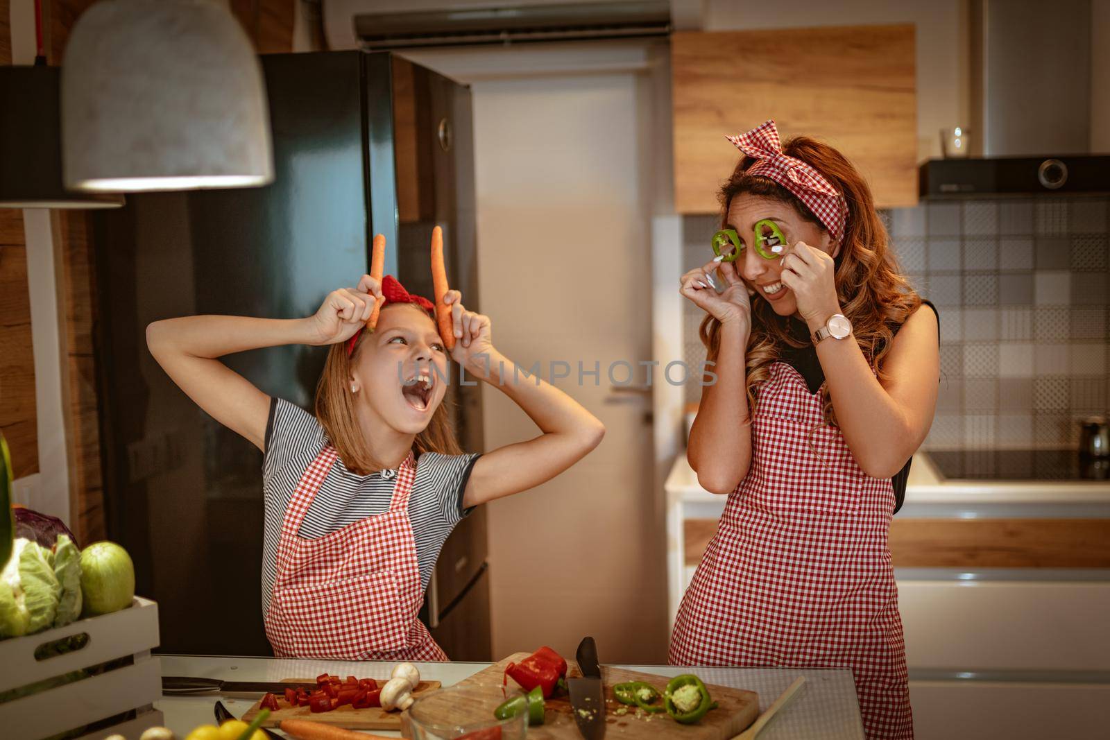Happy mother and her daughter enjoy and having fun in making and having healthy meal together at their home kitchen.