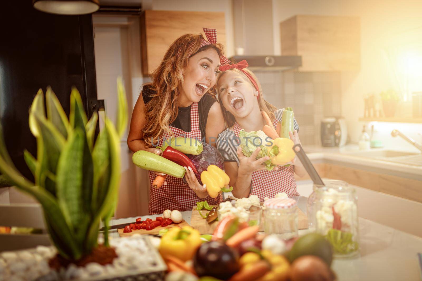 Happy mother and her daughter enjoy preparing for marinating vegetables and making healthy meal together with fun, at their home kitchen.  