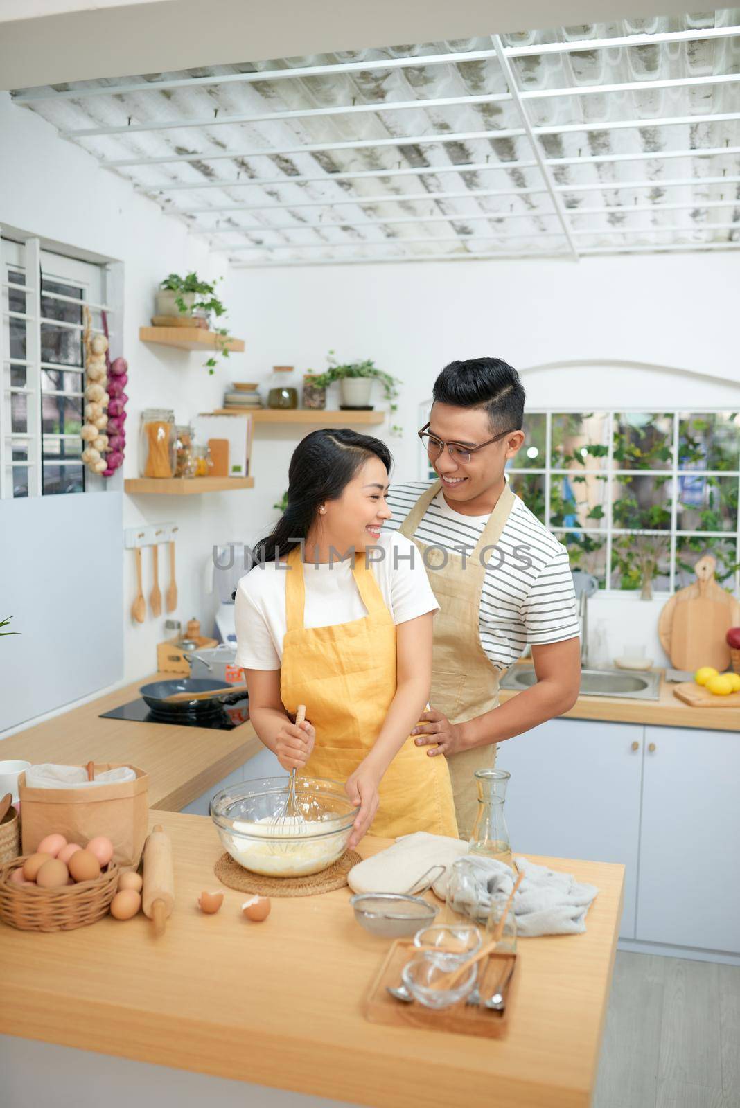 Couple man and woman wearing aprons having fun while making homemade pasta in kitchen at home by makidotvn