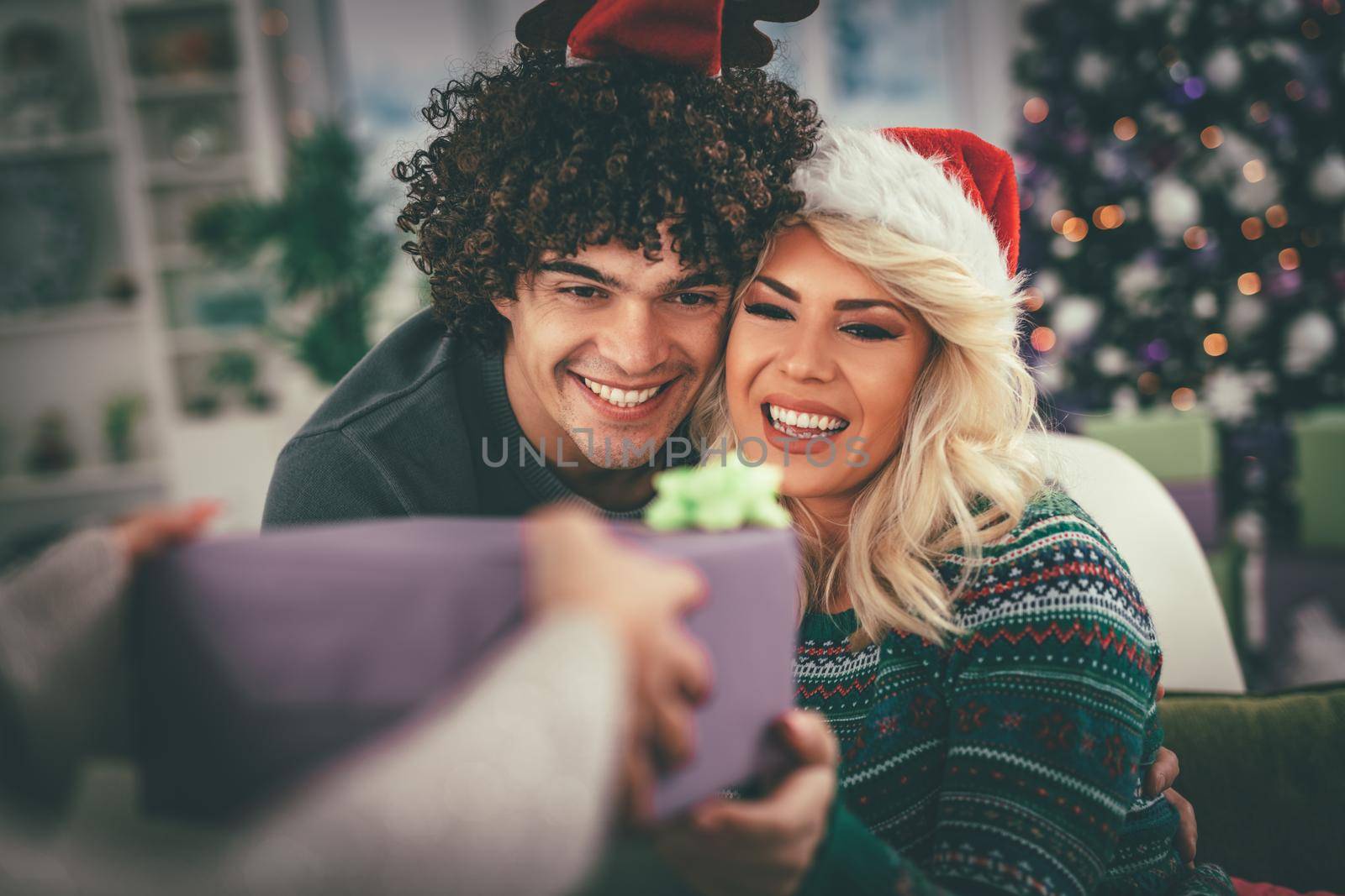 Loving couple in cozy warm sweaters on a Christmas New Year eve, smiling and having fun with each other eating popcorn. Selective focus. 