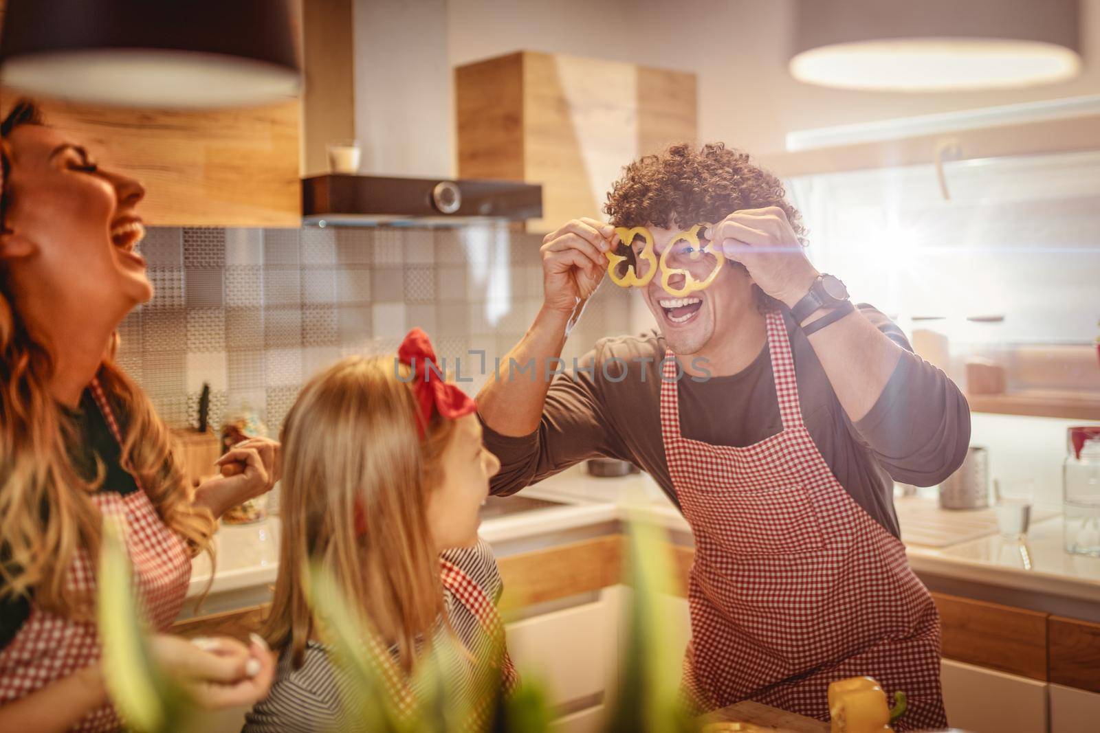 Happy parents and their daughter enjoy and having fun in making and having healthy meal together at their home kitchen.