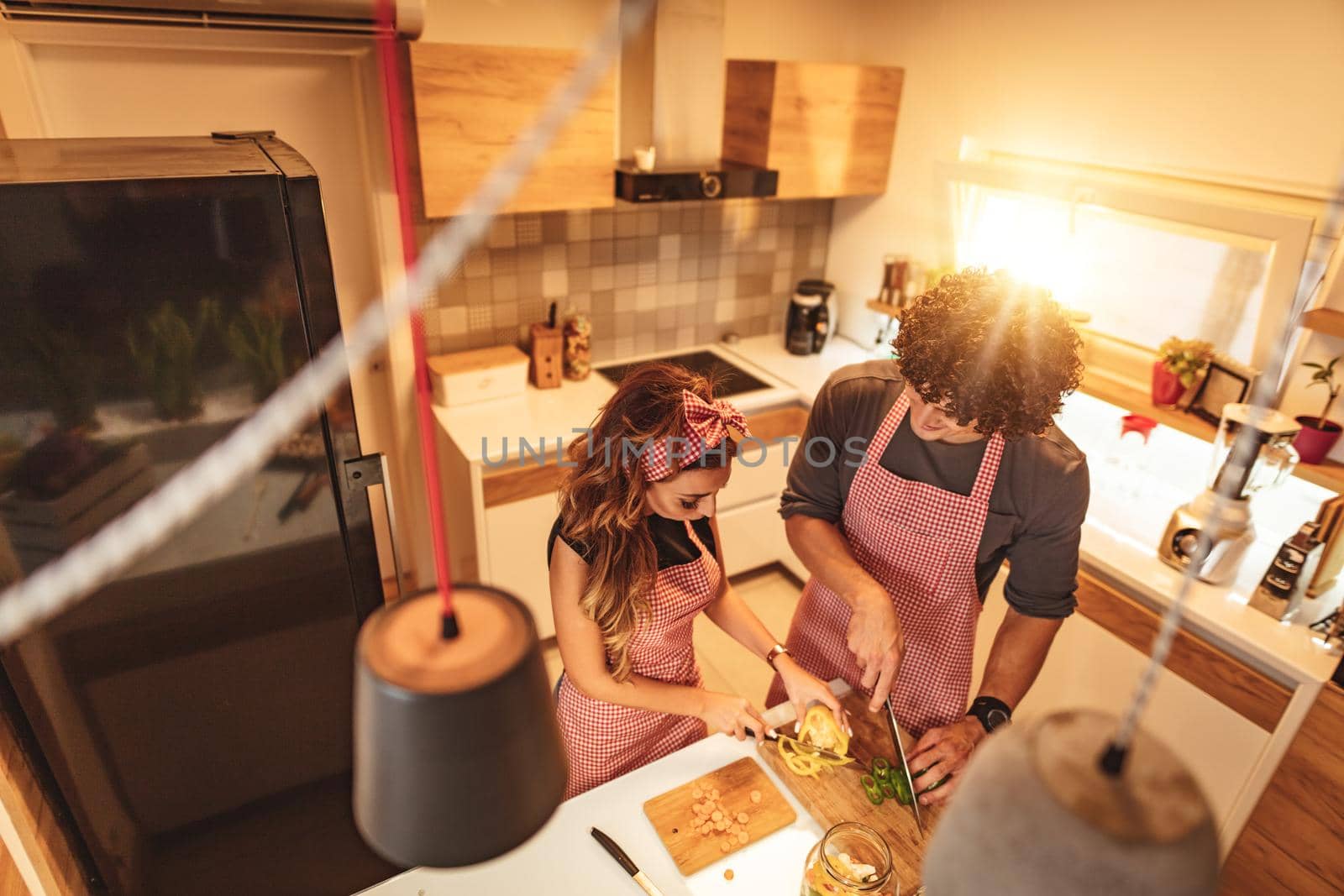 Cute couple is putting vegetables in a jar and smiling while making pickle in kitchen at home