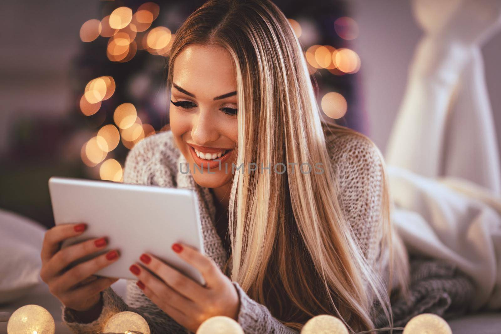 Cute young smiling woman using tablet and happy smiling  during cozy Xmas holidays at home.