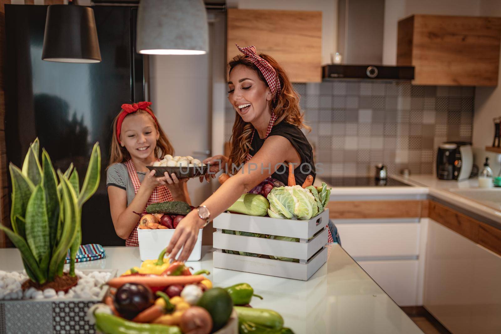 Happy mother and her daughter enjoy making and having healthy meal together at their home kitchen.