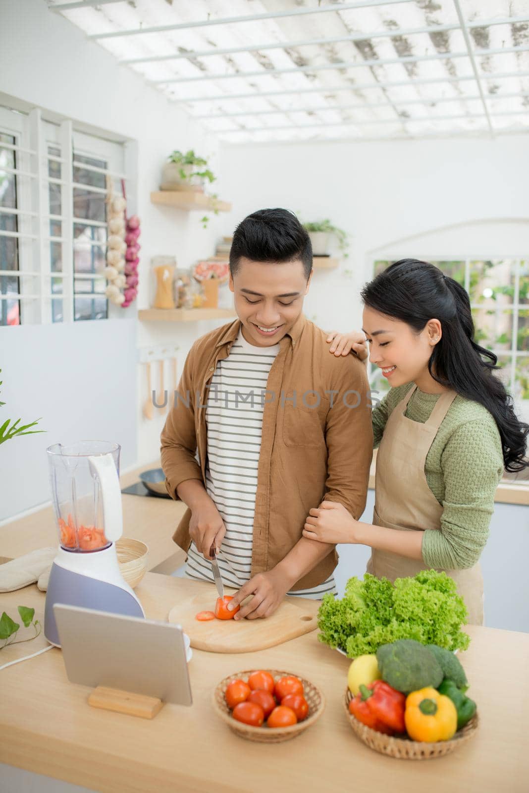 Portrait of a pretty young couple cooking together according to a recipe on a tablet computer
