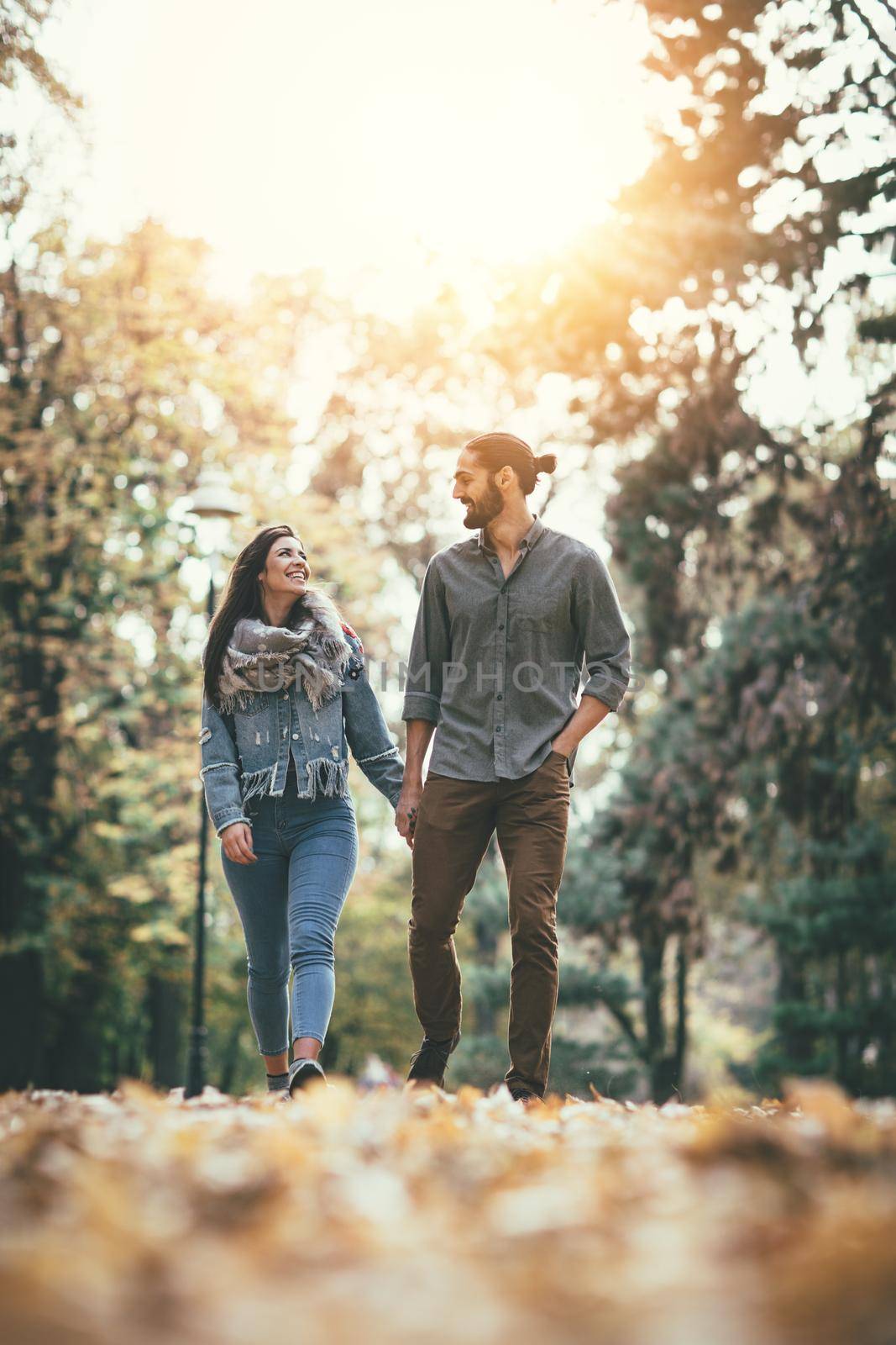 Beautiful smiling couple enjoying in sunny city park in autumn colors looking each other.