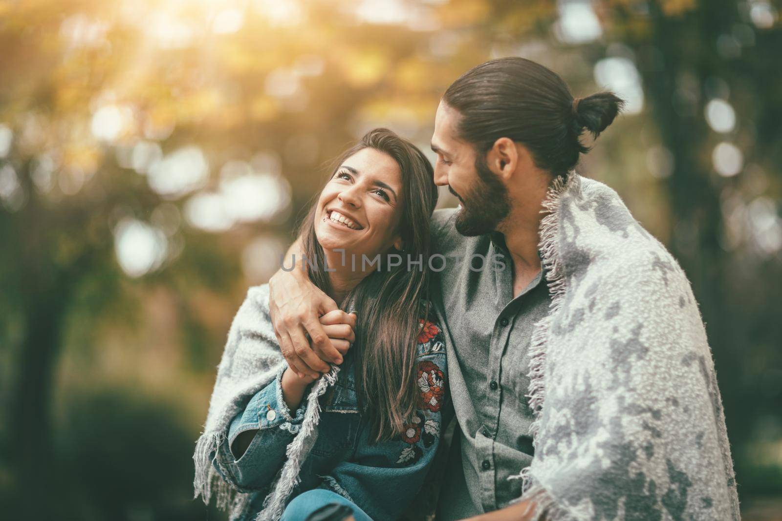 Beautiful smiling couple enjoying in sunny city park in autumn colors looking each other.