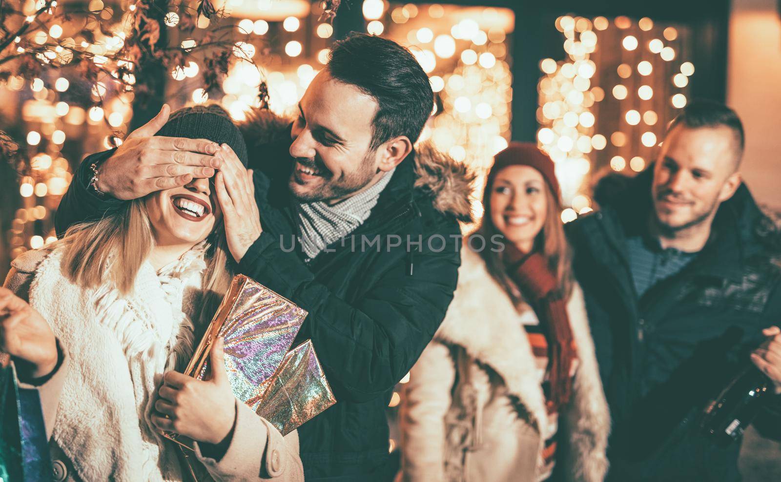 Man keeps his girlfriend eyes covered while she giving a gift for Christmas holiday. Selective focus. Focus on foreground.