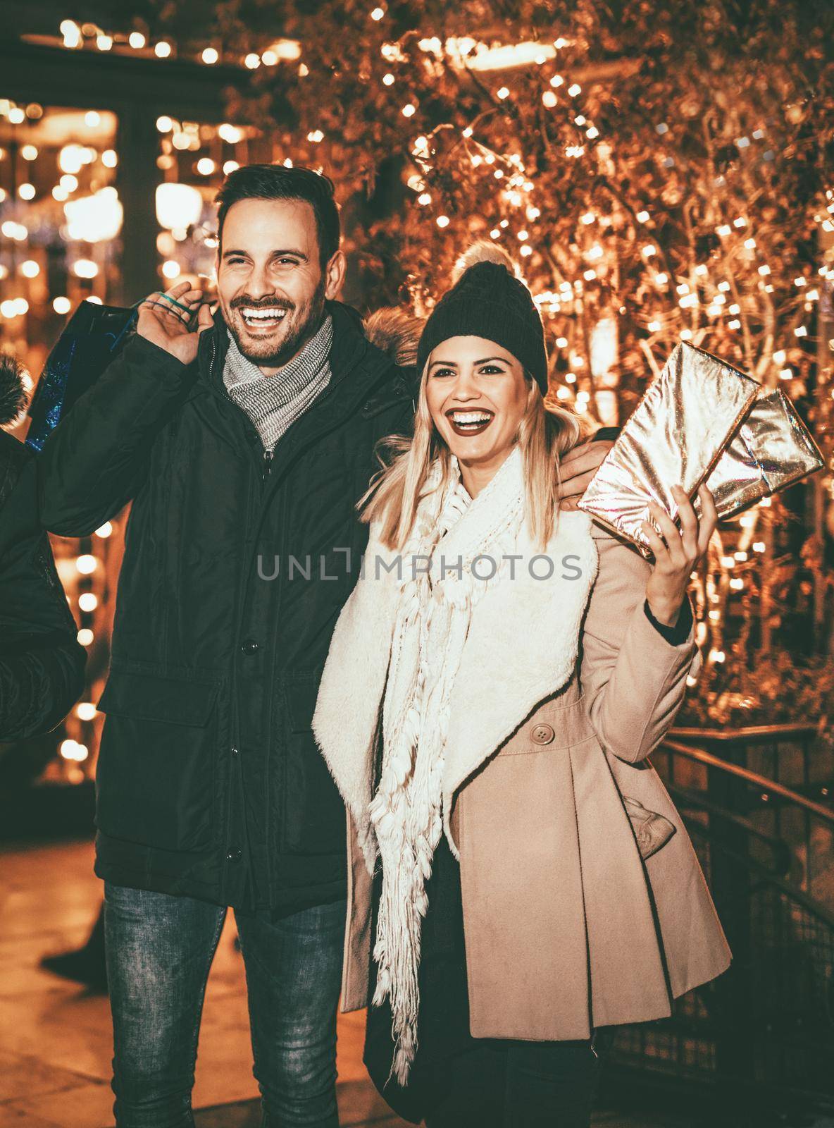 Happy attractive loving couple enjoy shopping together in holiday night.