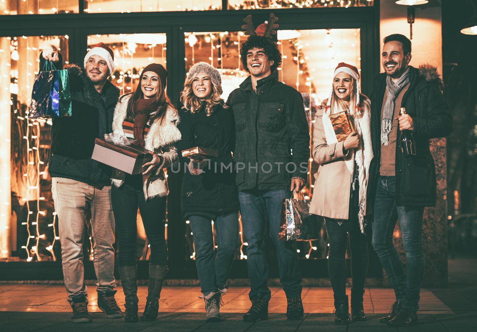 Young smiling friends having fun in the city street and going to Christmas party.