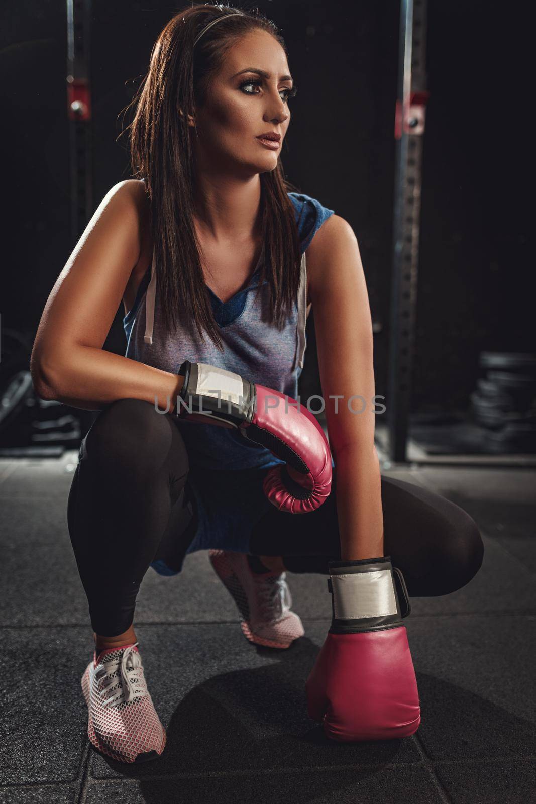 A cute young woman is resting after boxing training at the gym. 