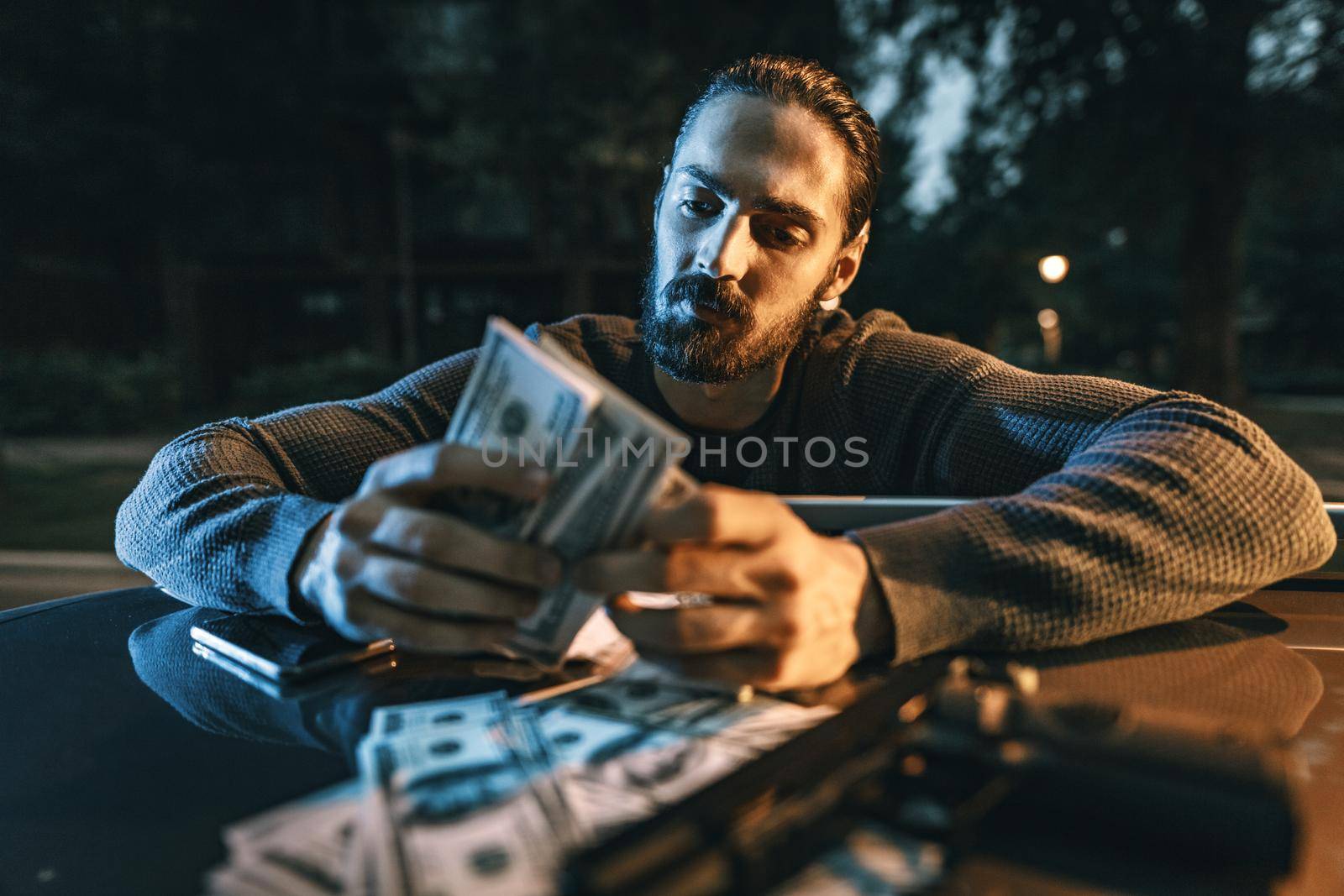 Dangerous criminal man is holding a gun and counting the money after criminal job done.