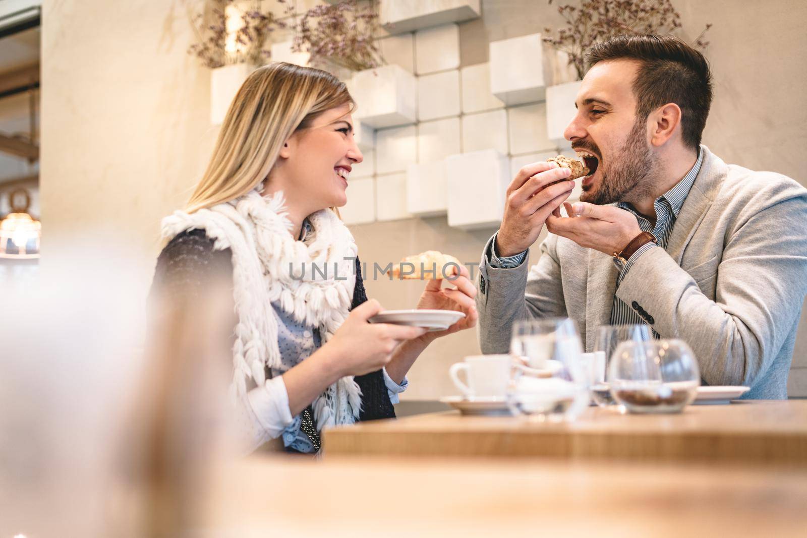 Young man and young woman sitting at cafe and talking with smile. They drinking coffee and having breakfast.