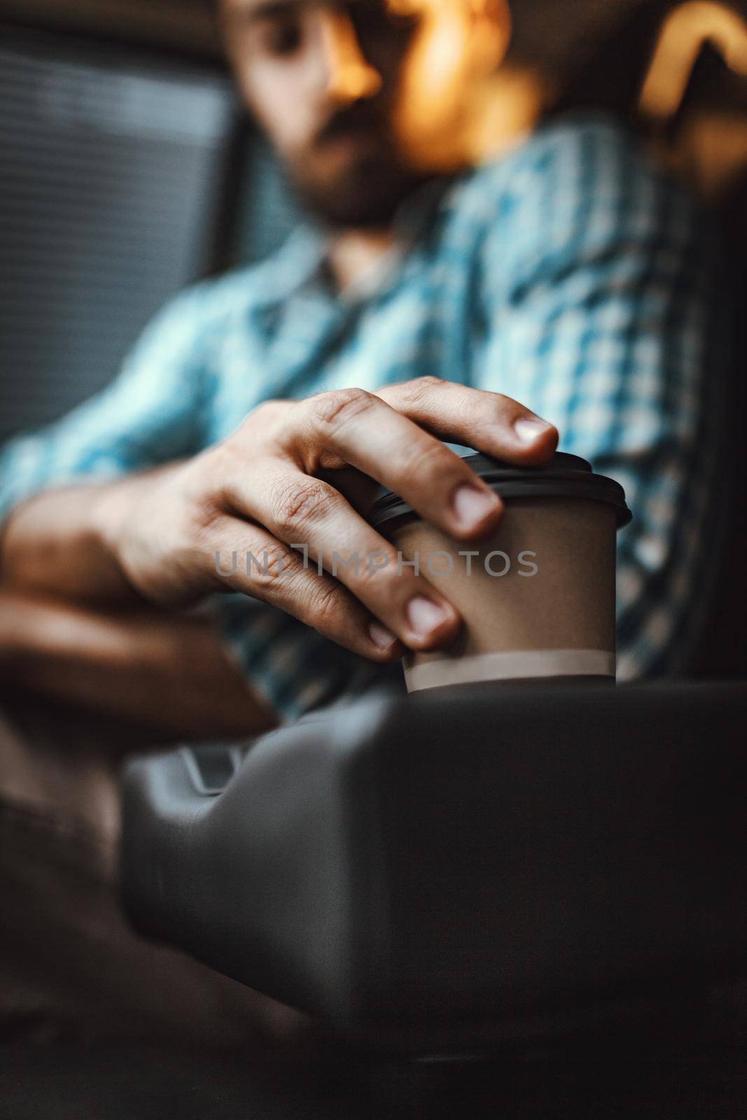 Close-up on a man's hand holding a cup of coffee, in car prepared for the trip.