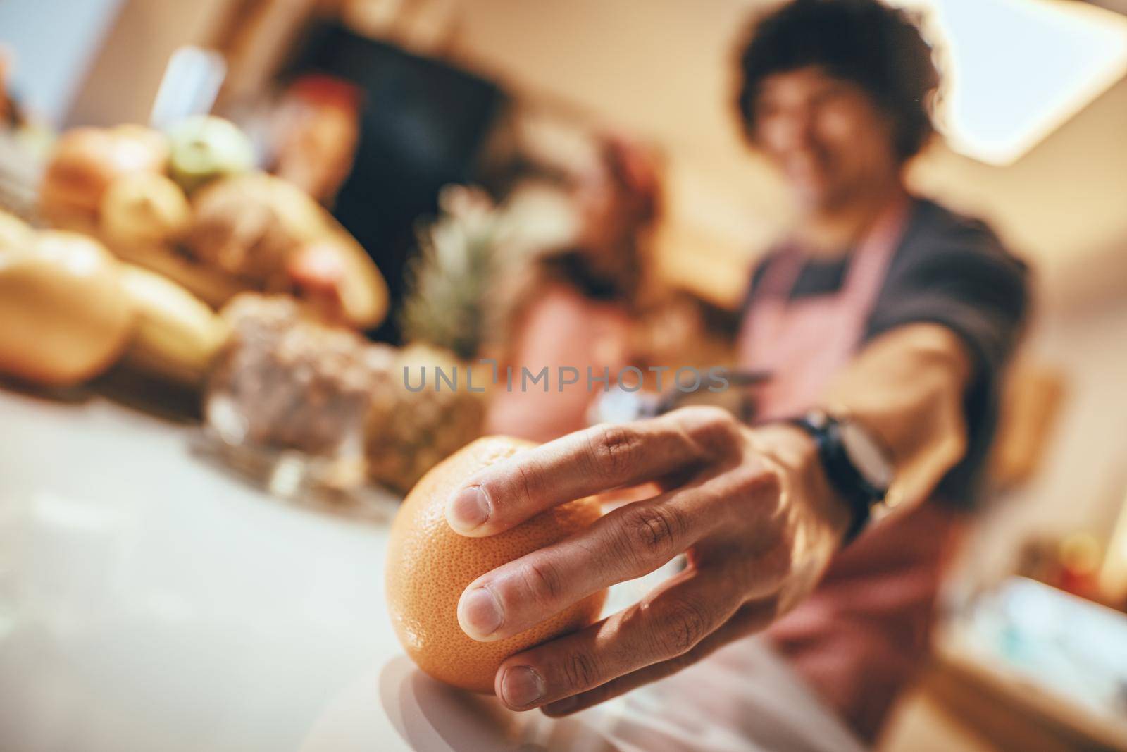 Close up on young man's hand holding mandarin in domestic kitchen.