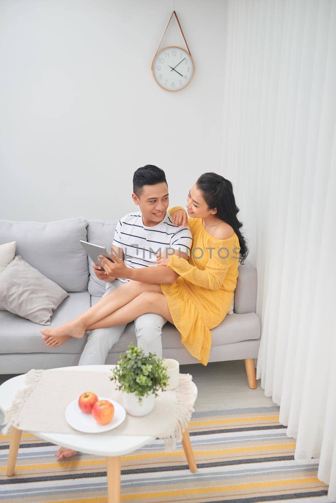 Young couple relaxing at luxurious home with tablet computers reading in the living room on the sofa couch.