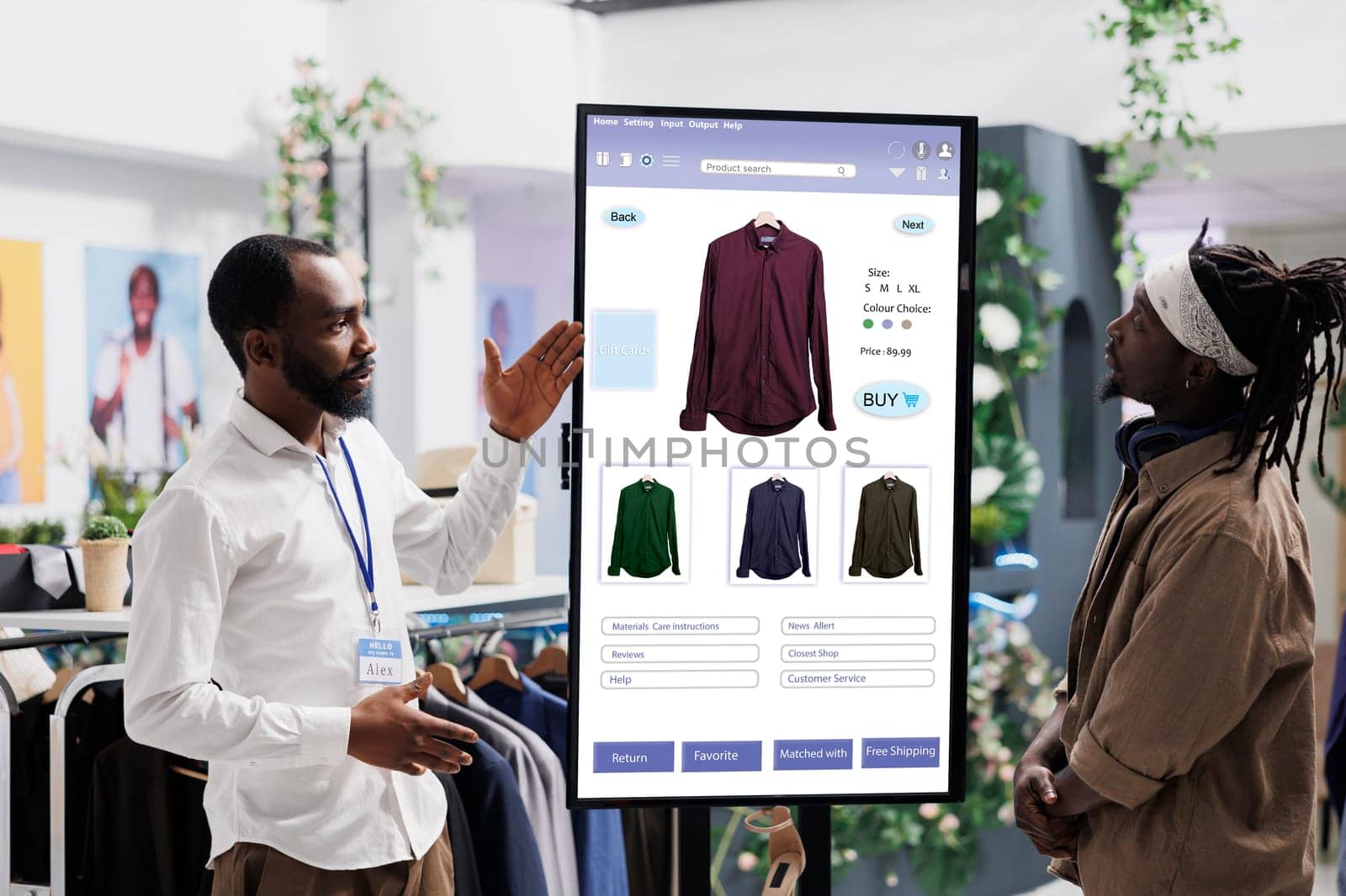 Male assistant showing clothes on interactive kiosk board to young trendy customer in clothing store at mall. Retail employee helping client to choose modern fashion items, self ordering.