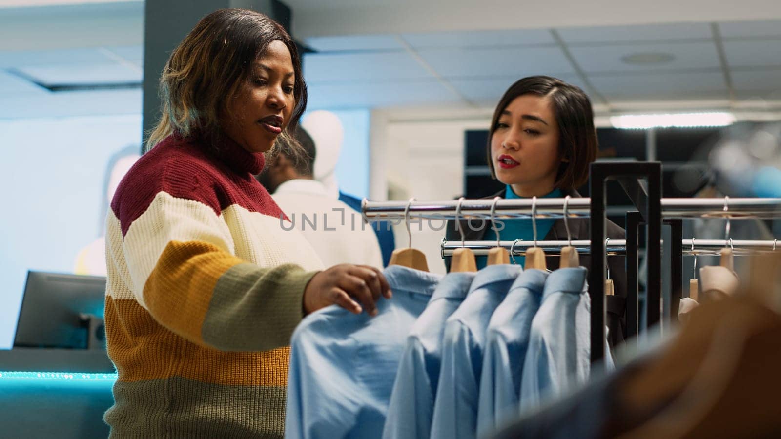 Female customer shopping for formal or casual wear, checking new fashion shop merchandise. Young adult checking boutique clothes in department store, small business. Handheld shot.