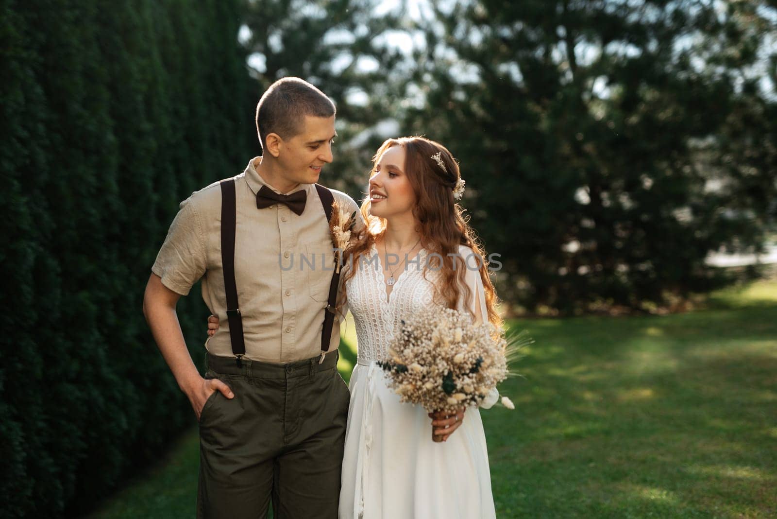 wedding walk of the bride and groom in a coniferous park in summer