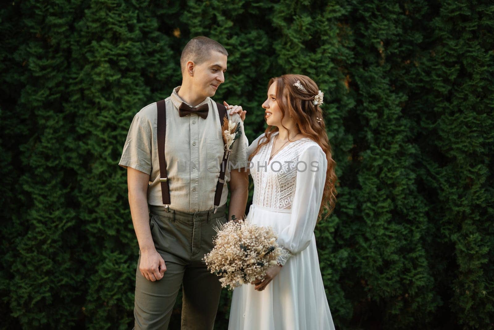 wedding walk of the bride and groom in a coniferous park in summer