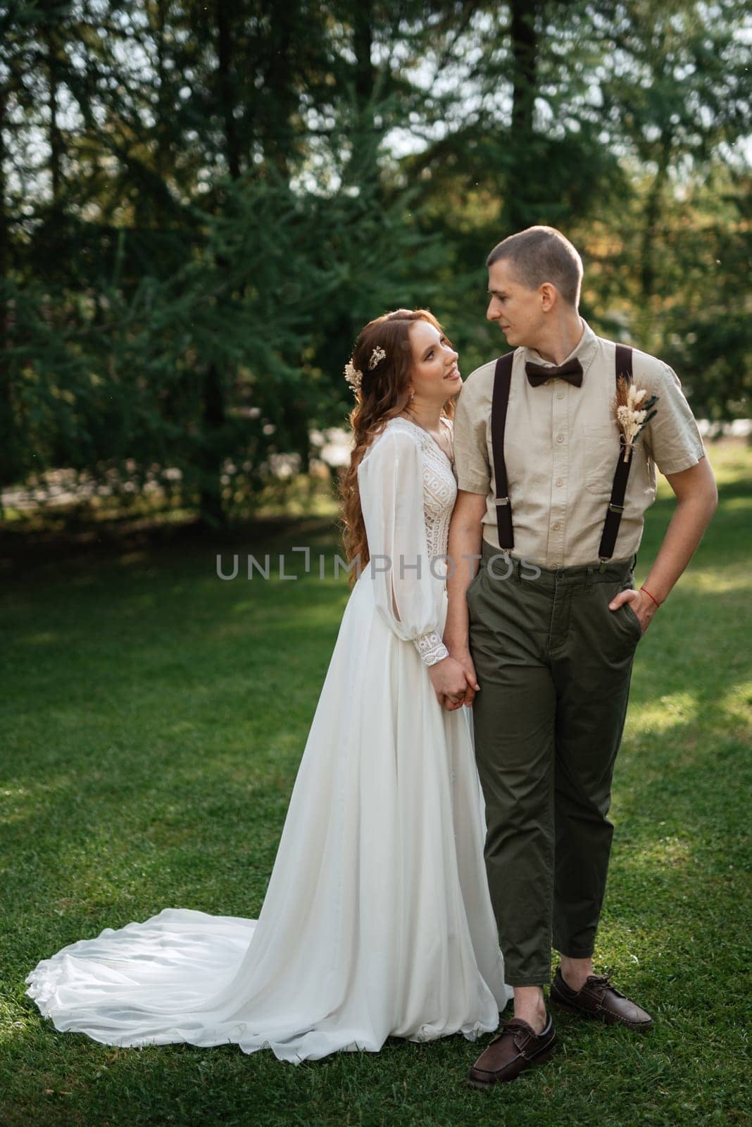 wedding walk of the bride and groom in a coniferous park in summer