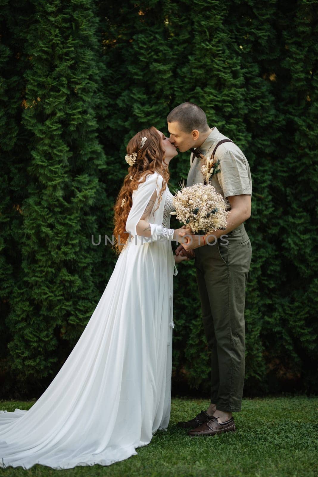 wedding walk of the bride and groom in a coniferous park in summer