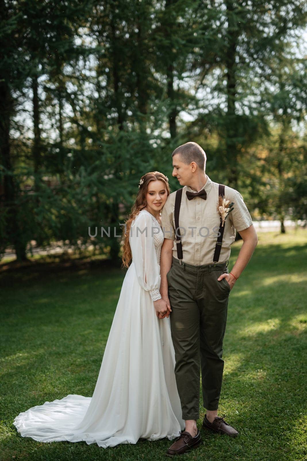 wedding walk of the bride and groom in a coniferous park in summer