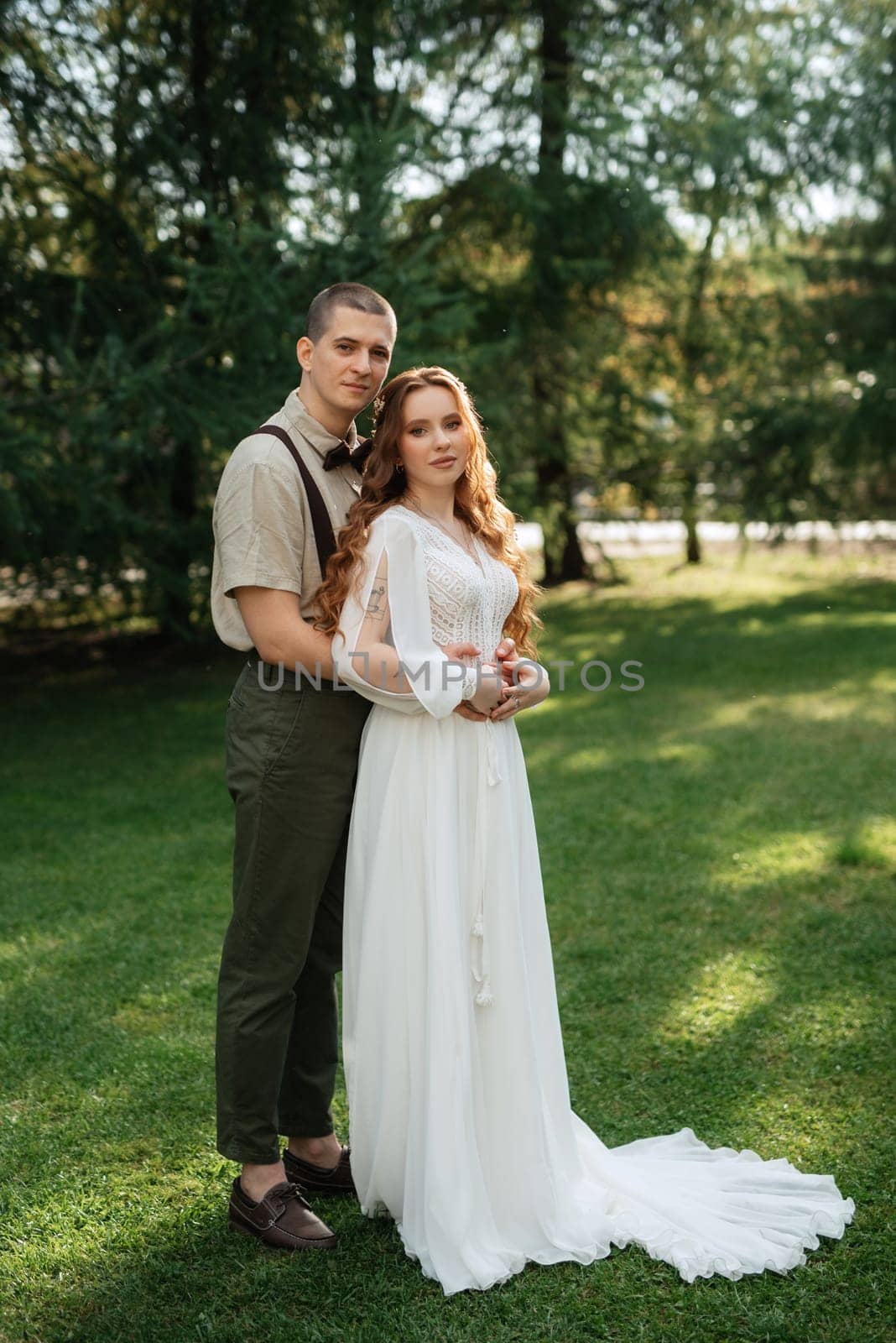 wedding walk of the bride and groom in a coniferous park in summer