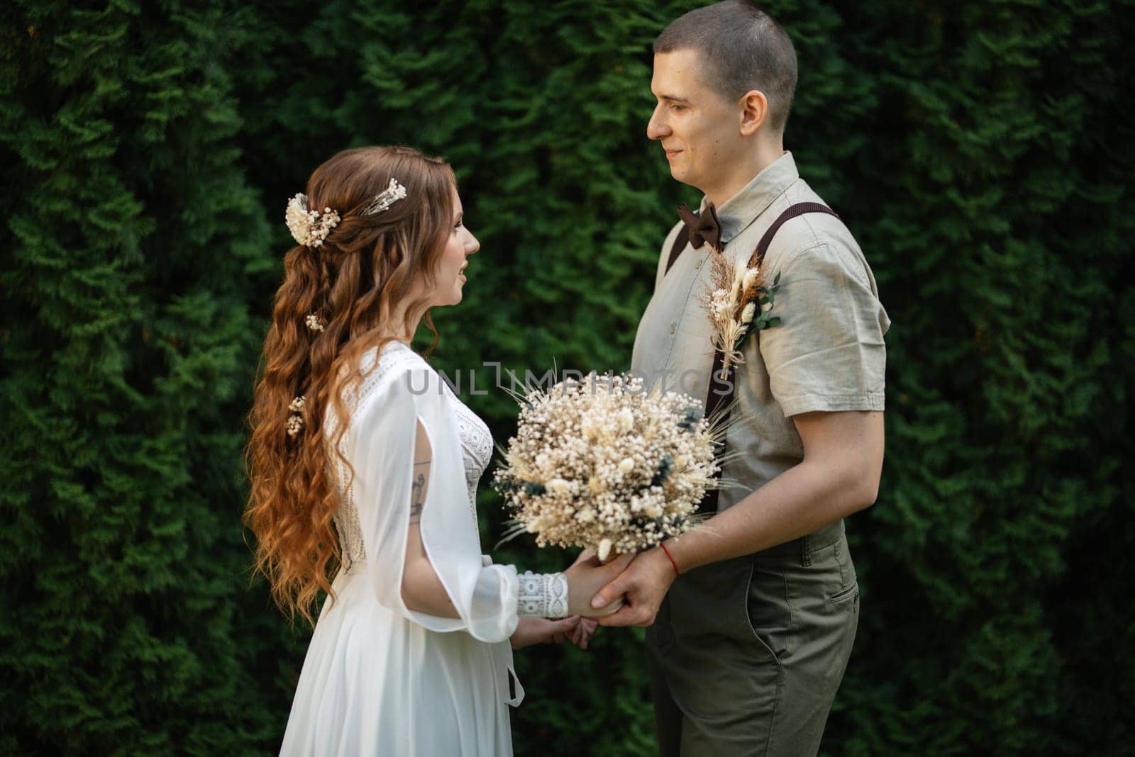wedding walk of the bride and groom in a coniferous park in summer
