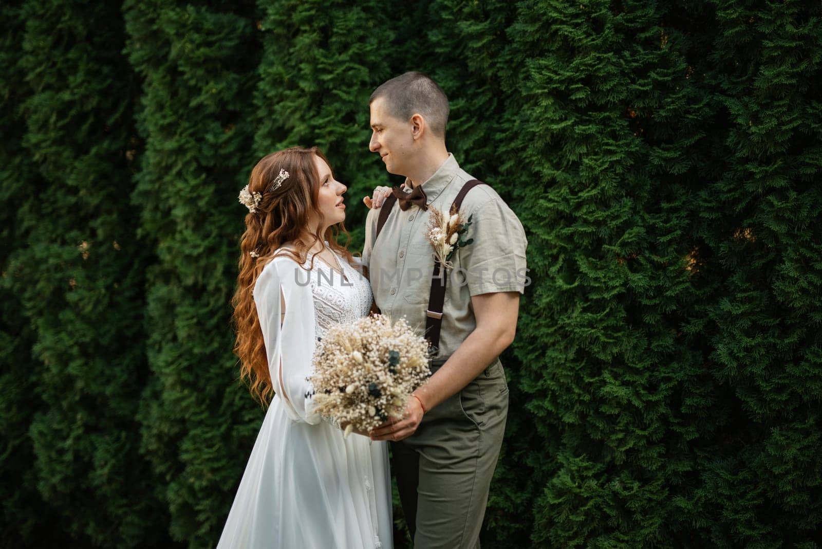 wedding walk of the bride and groom in a coniferous park in summer