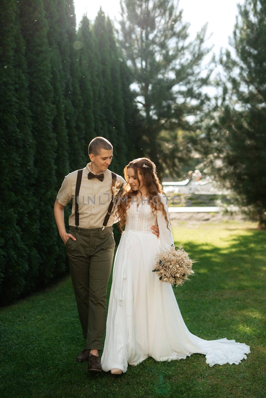 wedding walk of the bride and groom in a coniferous park in summer