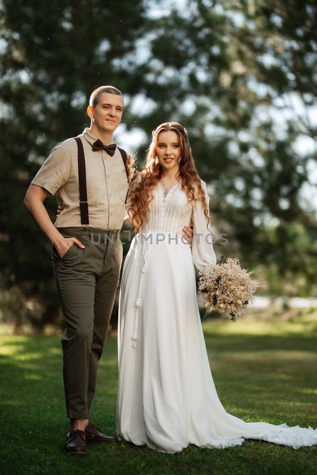 wedding walk of the bride and groom in a coniferous park in summer